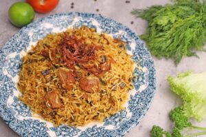 Aromatic chicken biryani served with colorful herbs and vegetables on a decorative plate.