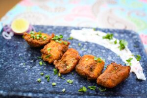 A vibrant plate of Indian fish tikka garnished with herbs, captured in a close-up shot.