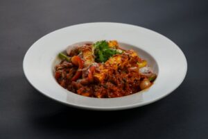 Close-up of a flavorful Indian paneer dish with vegetables served on a white plate, perfect for dining ambiance.