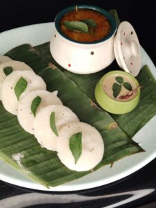 Delicious South Indian idli served on banana leaves with sambar and coconut chutney.