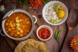 Appetizing chickpea curry with roti and accompaniments in a vibrant food flat lay.
