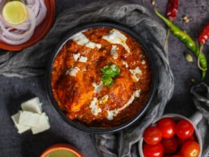 Savory paneer makhani dish with rich tomato sauce and fresh garnishes captured in an overhead shot.